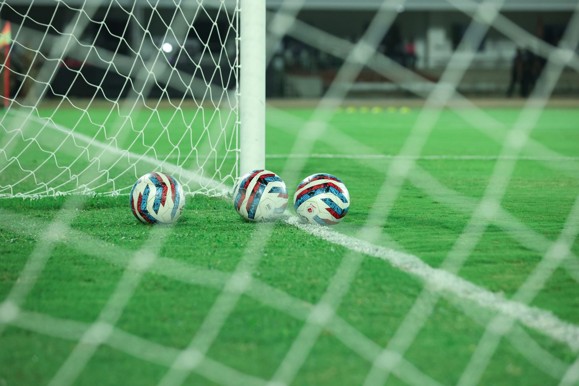 two soccer balls sitting on a soccer field