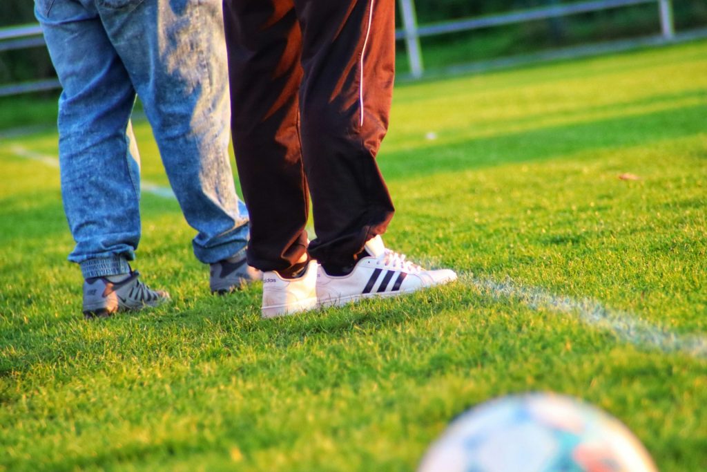 a pair of people's legs and shoes on a grass field