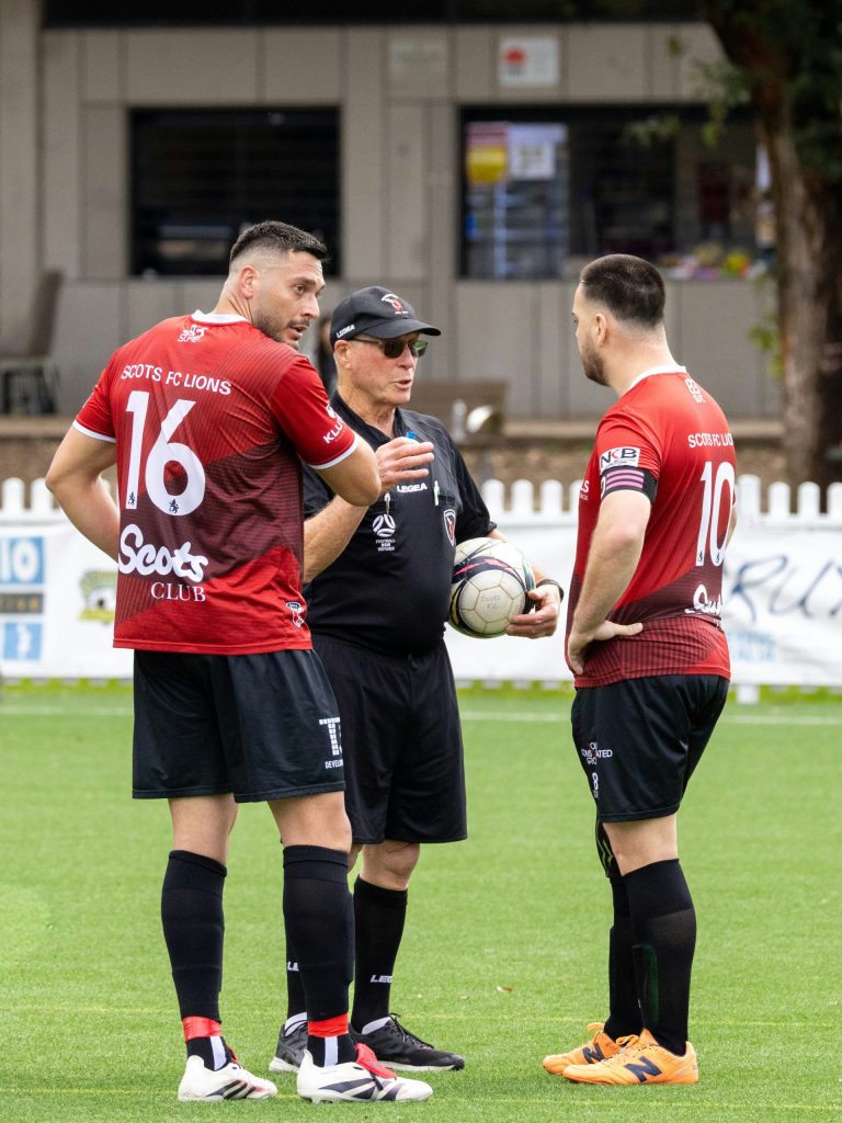 Soccer referee talks to two players on field